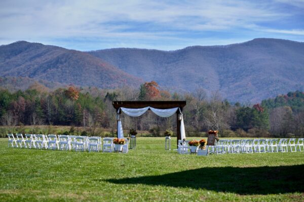 Outdoor wedding ceremony with guests seated on wooden benches among the mountains