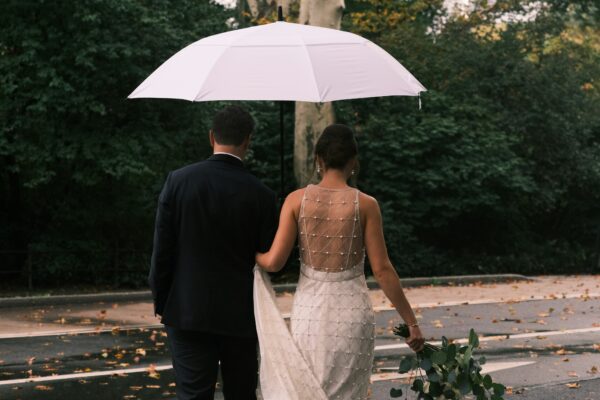 Bride and groom under an umbrella on a rainy wedding day
